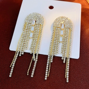Macro shot of silver rhinestone tassel earrings featuring crystal studs on a red texture