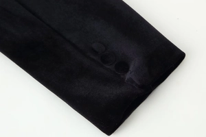 Détail du poignet d'un blazer en velours noir avec trois boutons recouverts de tissu