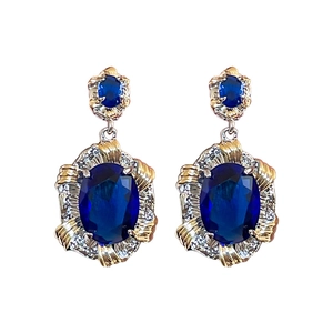 Deep blue oval sapphire earrings with gold accents and sparkling diamond cluster detailing