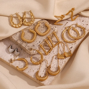 Golden and silver geometric hollow Z-shape earrings on beige stone and silk