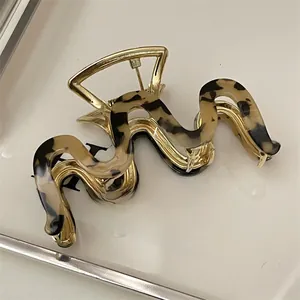 Detail of golden metal hair claw with wavy tortoise shell acetate pattern and strong spring