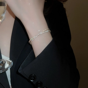 Détail d'un bracelet double couche en or avec zircons blancs porté au poignet par un mannequin