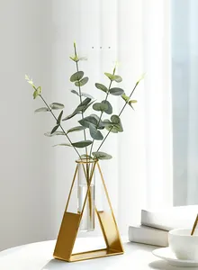 Close-up of golden triangular metal stand with glass test tube vase for hydroponics