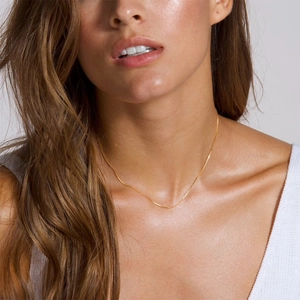 Close-up of a delicate gold twist chain necklace worn by a model to show elegant fit