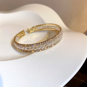 Detail of gold open bracelet with three-row inlay of clear beads and sparkling crystals