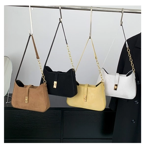 Four suede crossbody bags in brown, black, yellow, and white with gold metal locks