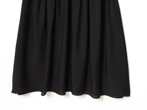 Vue détaillée de l'ourlet de robe noire avec texture horizontale et design plissé