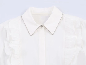 Detail of white poplin shirt featuring ruffled front and silver collar chain decoration