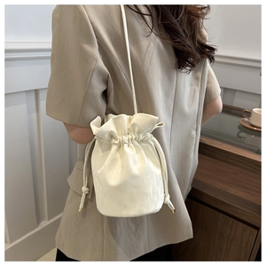 Detail of cream white bucket bag with drawstring closure and fine leather texture