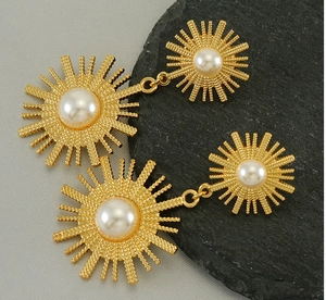 Détail macro de boucles d'oreilles perles soleil dorées avec texture métallique tissée