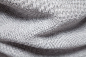 Macro shot of gray knitted fabric texture showing fine weave patterns on a men sweater