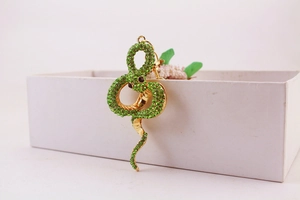Close-up of a creative snake keychain with green rhinestones and golden metal finish
