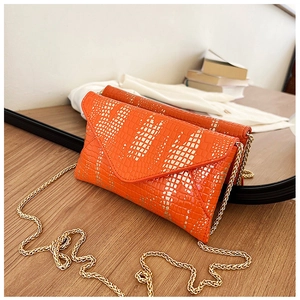 Close-up of orange crocodile pattern PU leather envelope bag with gold chain strap