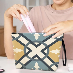 Portable geometric cosmetic bag with wristlet being packed in a cozy home setting