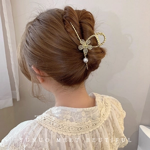 Detail of golden flower hair claw clip with rhinestones and dangling pearl on model
