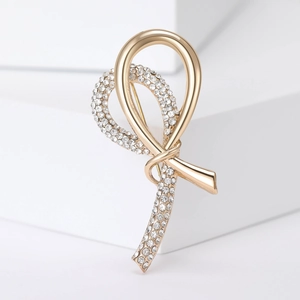 Macro shot of gold ribbon brooch with shimmering rhinestones on white geometric base