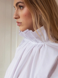 Detailed view of white ruffled stand collar shirt with elegant pleated texture design