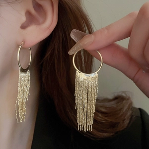 Close-up of gold plated circle earrings with long tassel chains on a model