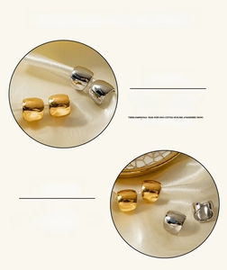 Polished stainless steel hoop earrings close-up on beige silk showing vacuum plating texture