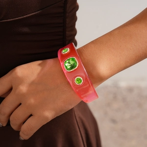 Detailed view of pink resin wide bangle featuring green gemstone inlay on a wrist