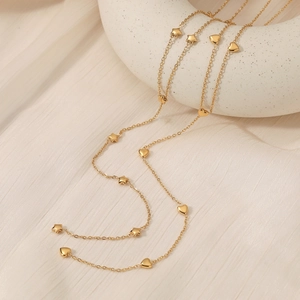 Elegante goldfarbene Y-Kette mit Sternen und Herzen auf Seidenhintergrund