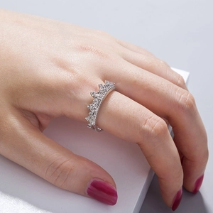 Detail of silver crown ring with white zircon stones worn on model's middle finger