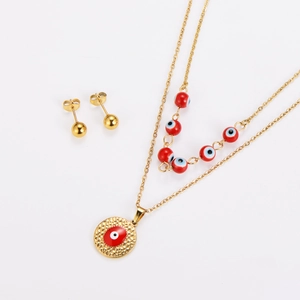 Detail of gold evil eye jewelry set with layered red bead necklace and ball earrings