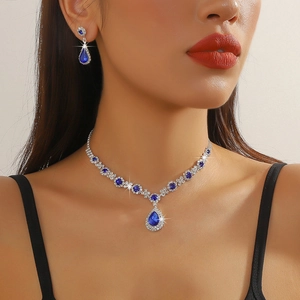 Detailed close-up of blue teardrop crystal necklace and earring set on female model