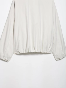 Detail van de crème jas met elastische zoom en oversized manchetten in matte afwerking