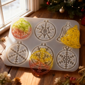 6-hole silicone mold for snowflake and bell Christmas resin pendants on a sunny desk