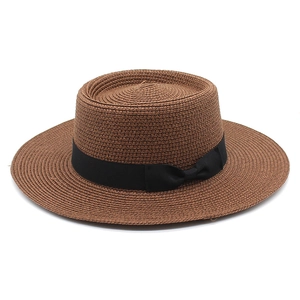 Detail of a brown boater straw hat featuring a black satin bow and fine spiral weaving