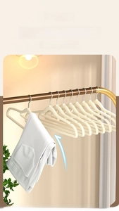 Non-slip cream flocked hangers organized on a gold rack with a white hoodie hanging