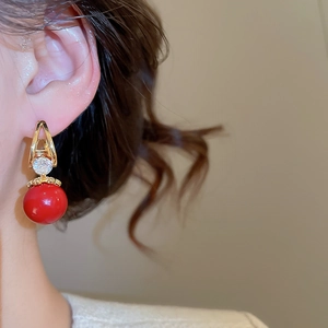 Détail d'une boucle d'oreille en zircon rouge sur modèle avec crochet doré et style rétro