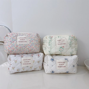 Détail de quatre trousses de maquillage matelassées à fleurs en tissu doux avec zip