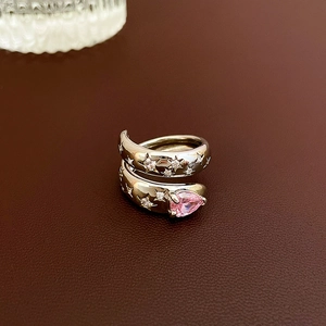 Macro shot of silver open ring with pink pear-cut stone and engraved star patterns