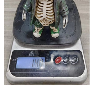 Close-up of stylish zombie skeleton figurine showing 140g weight on a digital scale