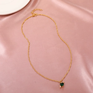 Macro shot of Cupid's Heart gold necklace with green heart gem on purple satin