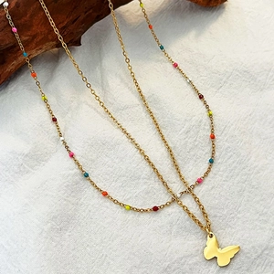 Double-layered gold butterfly necklace with vibrant colorful beads on white fabric