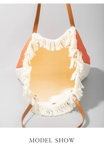 Detail of the woven beach tote bag with orange and white panels and long fringe trim