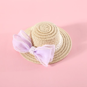 Macro view of woven straw pet hat with large purple mesh bow and pearl details