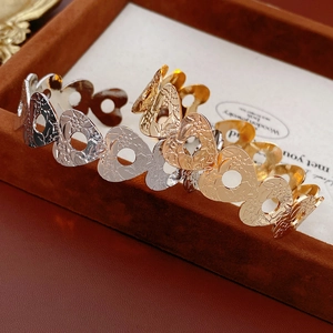 Detailed close-up of hollow heart embossed metal bangles in gold, silver, and rose gold