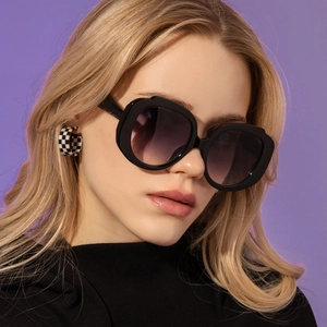 Close-up of black round oversized sunglasses with purple gradient lenses and checkered earrings