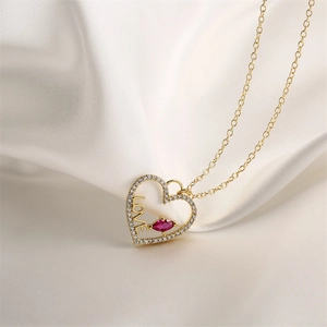 Gros plan du pendentif cœur plaqué or avec texte LOVE et pierre rouge sur soie blanche