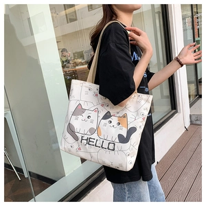 Lifestyle view of canvas tote bag with cat print and woven strap on a shoulder