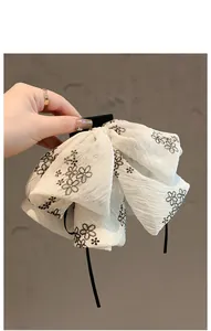 Détail d'un nœud papillon blanc avec broderie florale noire et texture ruban