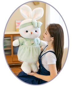 Young woman holding a large white plush rabbit toy wearing a green floral checkered dress