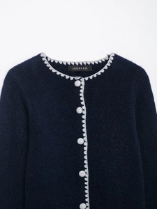 Close-up of navy knit cardigan with decorative scalloped trim and matching knit buttons