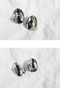 Detail of silver stud earrings with hammered texture and irregular oval metal shape