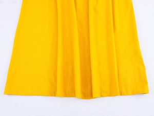 Detailed macro view of yellow cotton fabric texture and hemline of the elegant maxi dress
