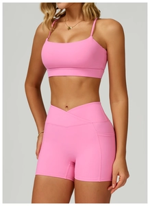 Detail of pink yoga set showing high-waisted shorts with side pockets and a racerback bra